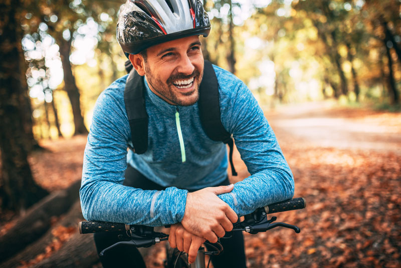 smiling man after ortho dental procedure on bike