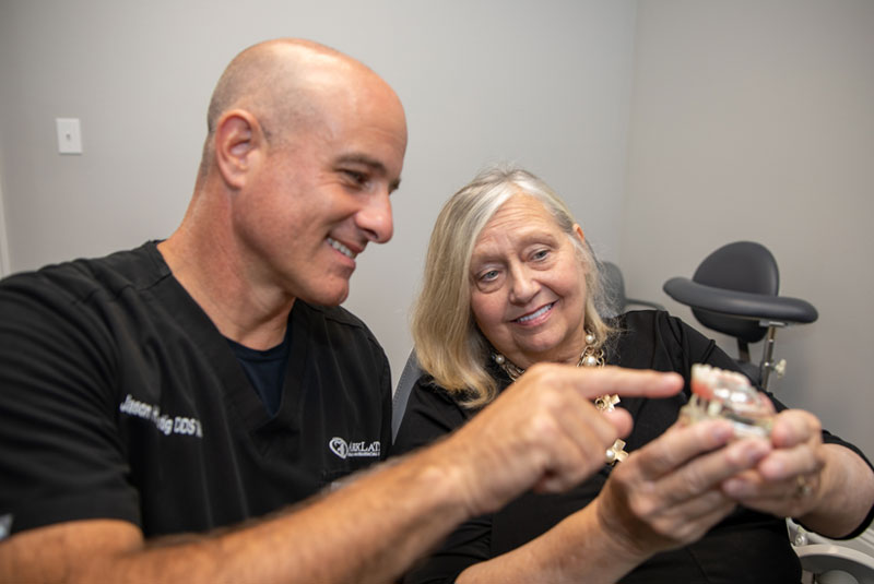 dr lustig showing implant model to dental patient